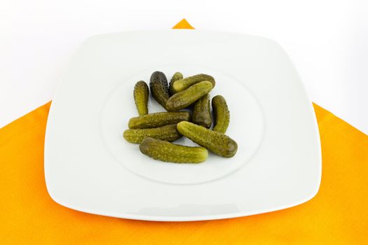 Pickled cucumbers in dish on white background.