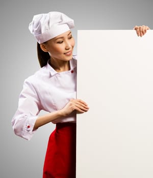 female chef holding a poster for text, look at the poster and smiling