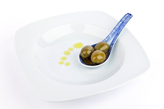Olives on  spoon and olive oil isolated on white.