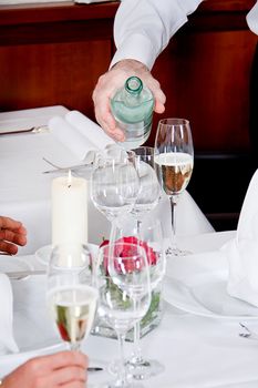 man and woman for dinner in restaurant waiter serving mineral water 