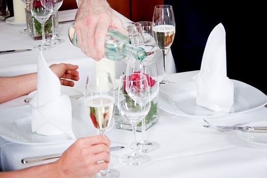 man and woman for dinner in restaurant waiter serving mineral water 