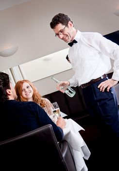 man and woman for dinner in restaurant waiter serving mineral water 