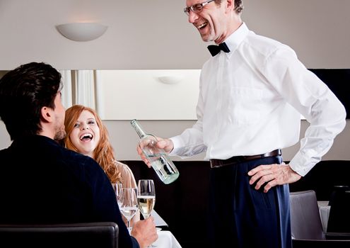 man and woman for dinner in restaurant waiter serving mineral water 