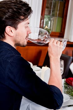 man and woman in restaurant for dinner drinking red wine and smiling