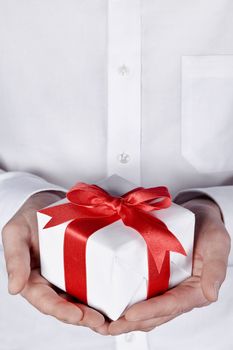 holidays giving, male giving a gift with red ribbon