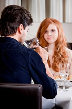 man and woman in restaurant for dinner drinking red wine and smiling