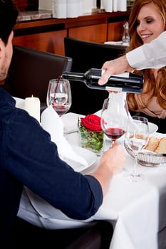 man and woman in restaurant for dinner drinking red wine and smiling