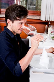 man and woman in restaurant for dinner drinking red wine and smiling