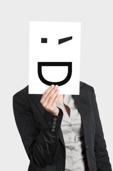Woman showing a blank paper with a smile winking in front of her face