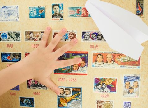 Child's hand on a background stamp collection on the theme of the cosmos