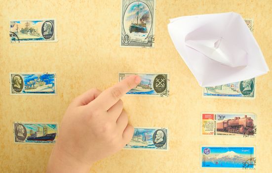 Child's hand on a background stamp collection on the theme of the  seafaring