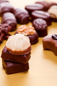 collection of different chocolate pralines truffels on golden brown background macro