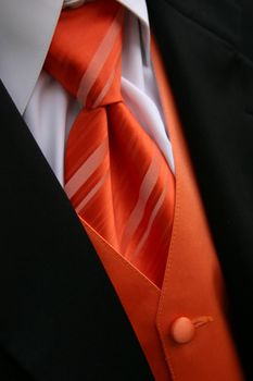 A closeup image of an orange tie, vest and tux