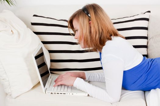 young teenager girl with laptop smilig ssitting on couch 