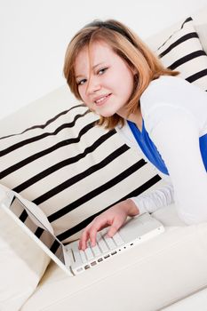 young teenager girl with laptop smilig ssitting on couch 