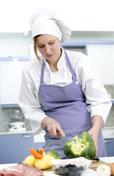Attractive chief cook preparing food , cuts broccoli