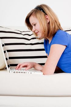 young teenager girl with laptop smilig ssitting on couch 