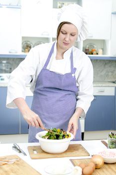 Attractive chief cook preparing salad