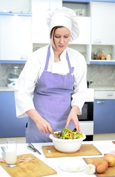 Attractive chief cook preparing salad