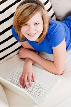 young teenager girl with laptop smilig ssitting on couch 