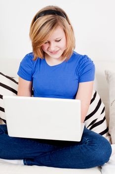 young teenager girl with laptop smilig ssitting on couch 