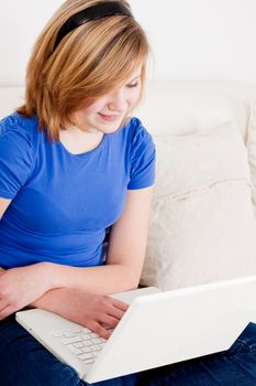 young teenager girl with laptop smilig ssitting on couch 