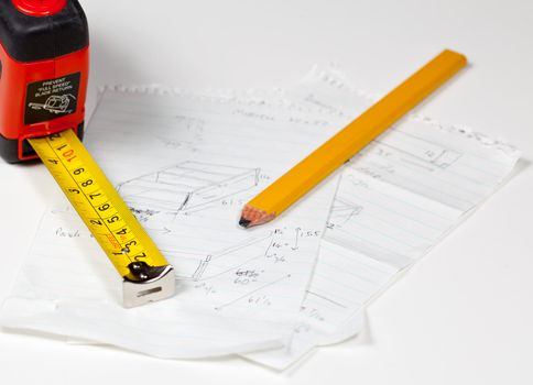 Tape measure and pencil laying on plans for a woodworking project
