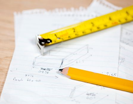 Tape measure and pencil laying on plans for a woodworking project