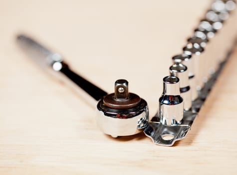 Wrench and miniature sockets in a holder on a piece of wood bench