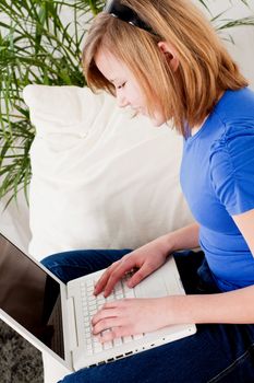 young teenager girl with laptop smilig ssitting on couch 