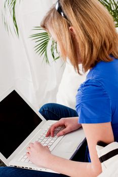 young teenager girl with laptop smilig ssitting on couch 