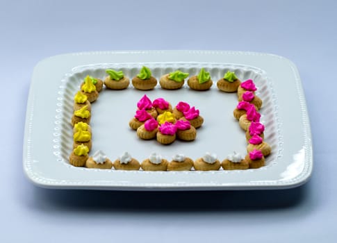 An arrangement of colorful icing topped cookies in white plate