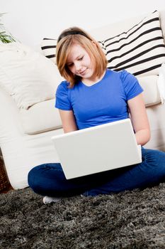 young teenager girl with laptop smilig ssitting on couch 