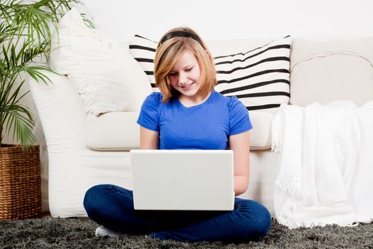 young teenager girl with laptop smilig ssitting on couch 