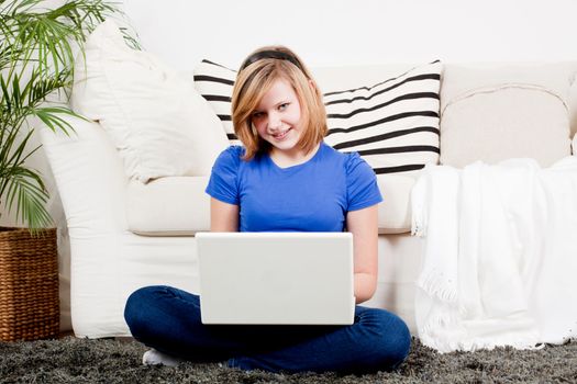 young teenager girl with laptop smilig ssitting on couch 