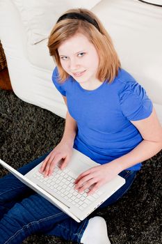 young teenager girl with laptop smilig ssitting on couch 