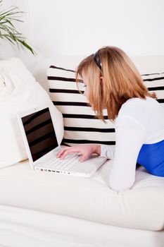 young teenager girl with laptop smilig ssitting on couch 