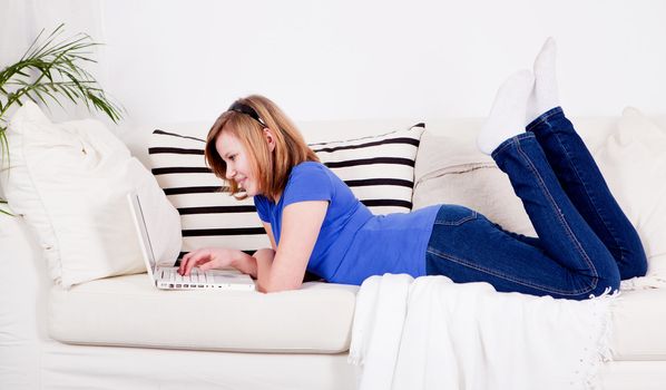 young teenager girl with laptop smilig ssitting on couch 