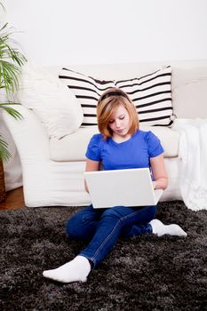 young teenager girl with laptop smilig ssitting on couch 