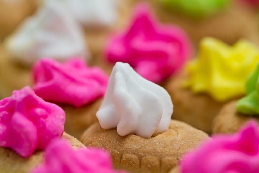 Close up view of the white color icing topped cookies with colorful icing topped cookies in background