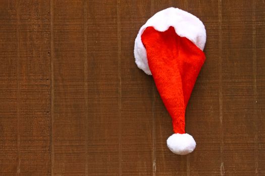 Iimage of Santa's hat hanging on a wooden backdrop with copy space. 