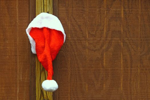 Iimage of Santa's hat hanging on a wooden backdrop with copy space.