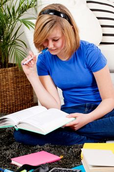 teenager girl sitting on the floor with lot of books and doing homework learning reading