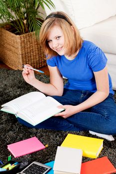 teenager girl sitting on the floor with lot of books and doing homework learning reading