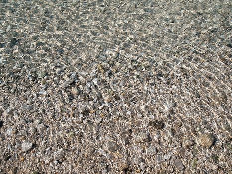 transparent water surface and sea stones on bottom 