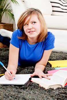 teenager girl sitting on the floor with lot of books and doing homework learning reading