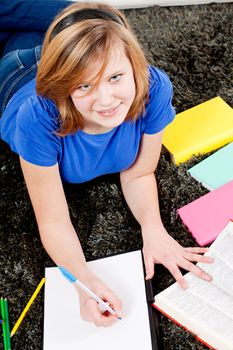 teenager girl sitting on the floor with lot of books and doing homework learning reading