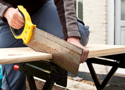 hands sawing wood