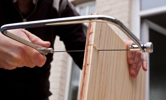 hands sawing wood