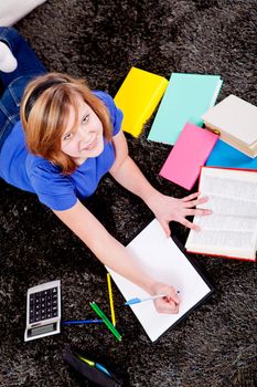 teenager girl sitting on the floor with lot of books and doing homework learning reading